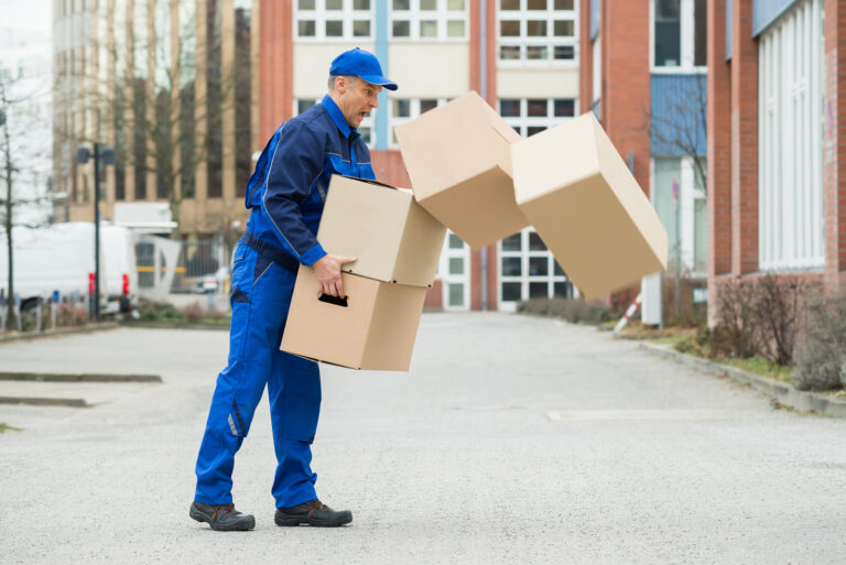 Delivery Man With Falling Stack Of Boxes On Street